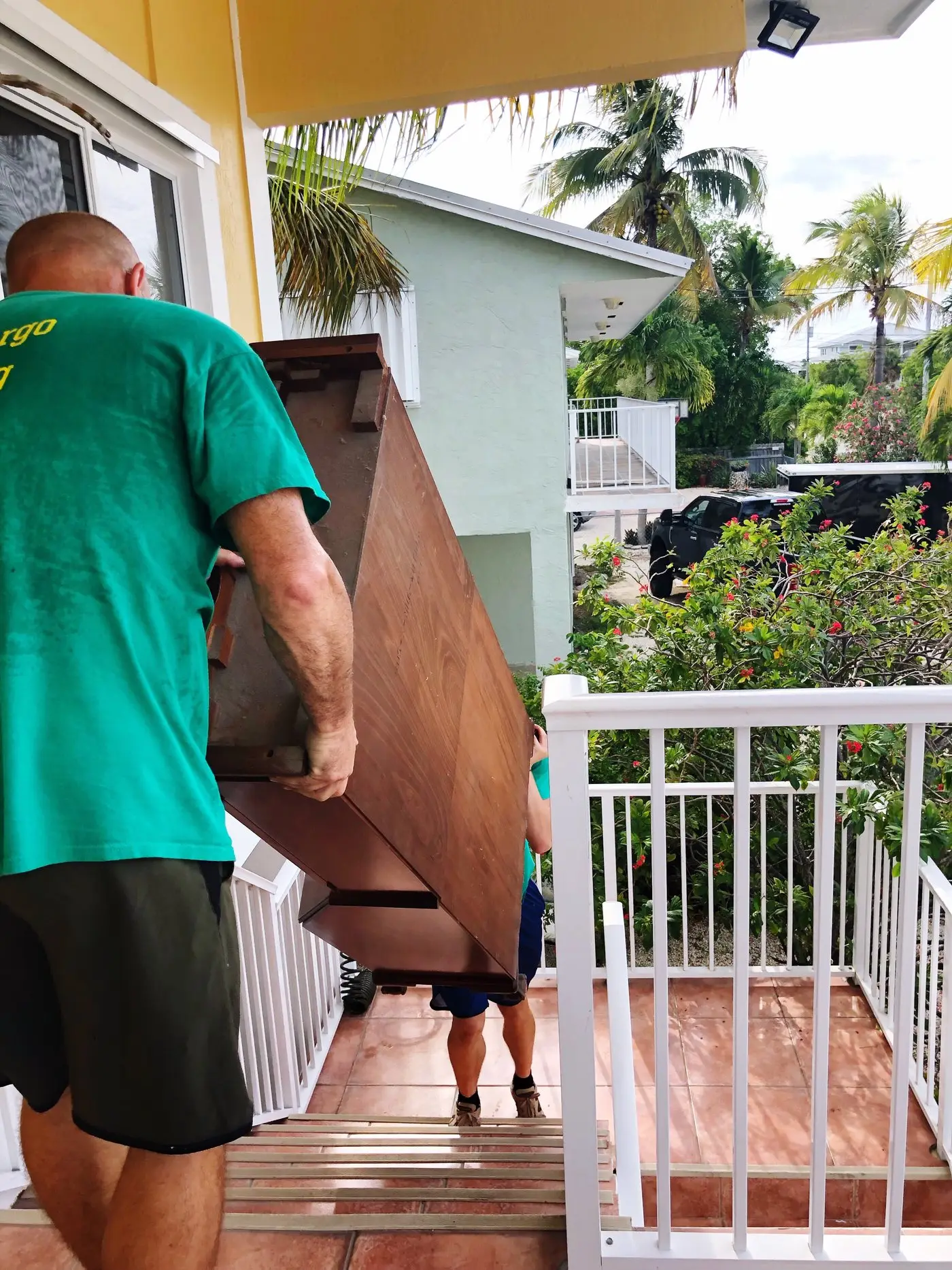 Two workers carefully moving furniture on exterior steps