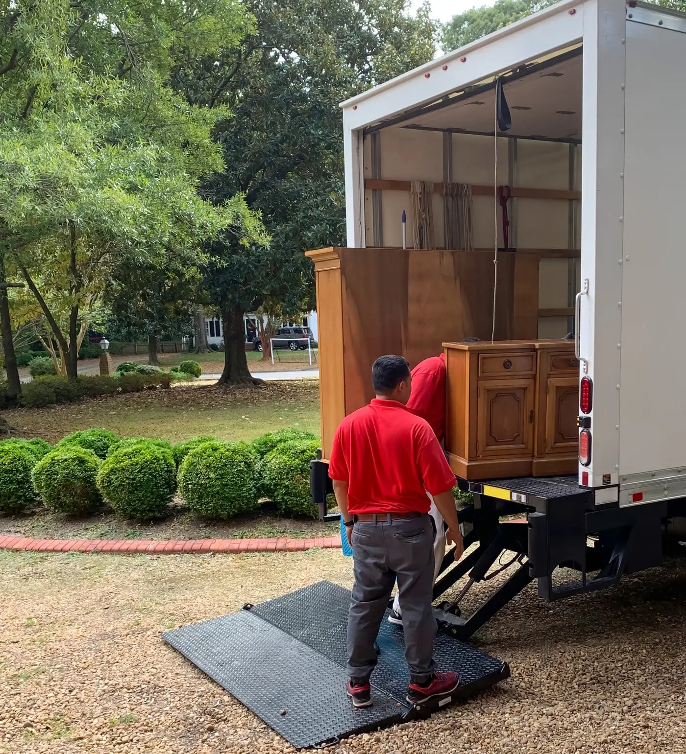 Junk removal crew loading wooden furniture into a box truck